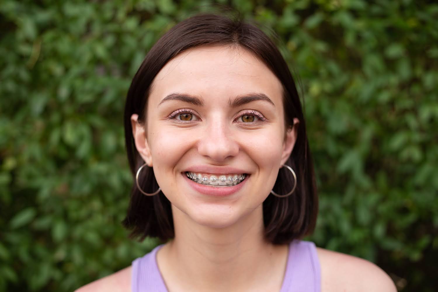 adult female patient smiling with traditional metal braces callan orthodontics