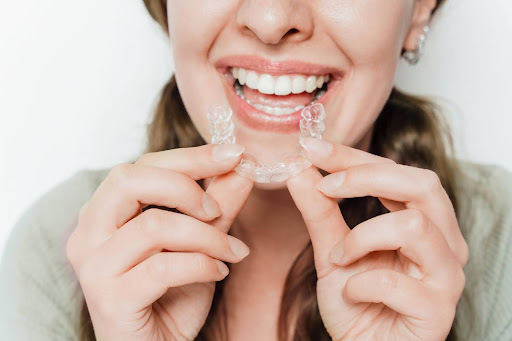 female patient closeup smiling holding invisalign invisable aligners callan orthodontics