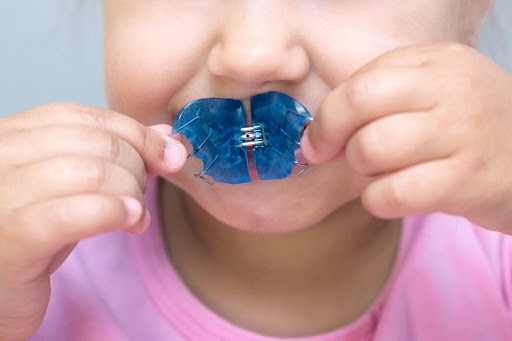 young girl smiling and holding palatal expander pediatric orthodontist callan orthodontics lawrenceville new jersey