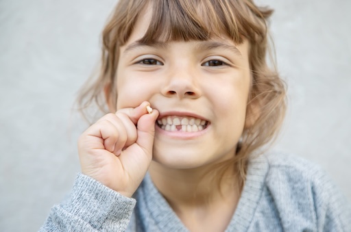 girl holding baby tooth